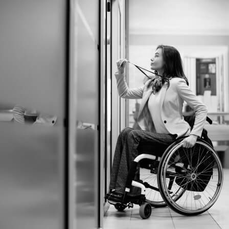 Personne en fauteuil roulant qui s'apprête à badger une porte