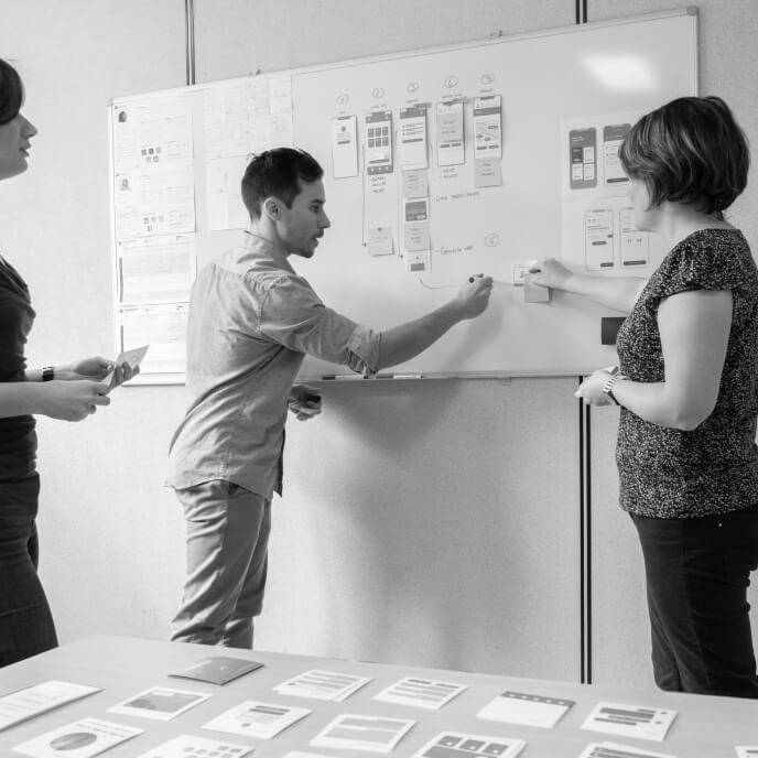Equipe design en présentation devant un tableau blanc
