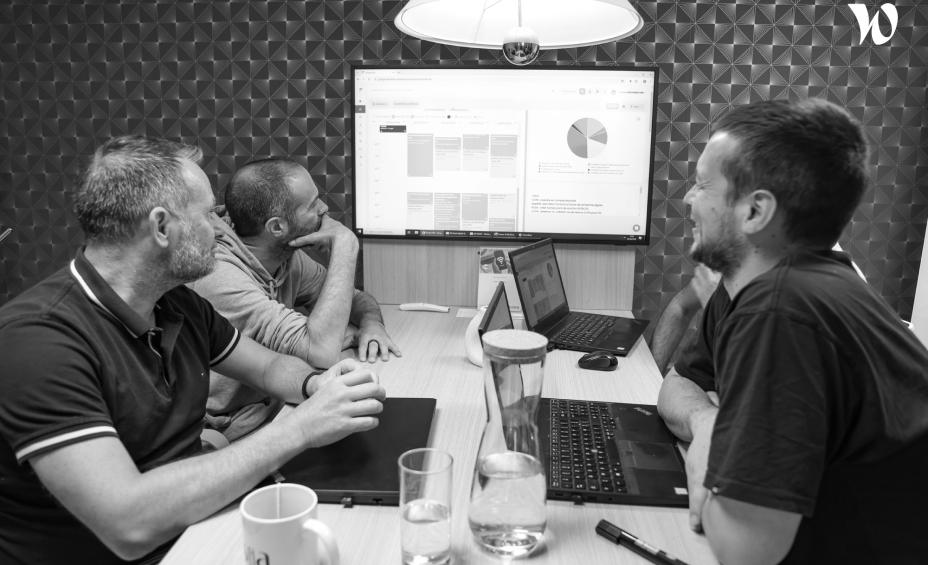 Groupe de travail assis autour d'une table face à un écran d'ordinateur